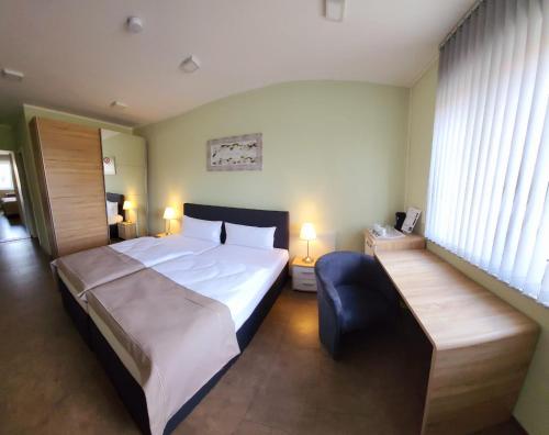 ein Schlafzimmer mit einem großen Bett und einem blauen Stuhl in der Unterkunft Lutz Motel in Paderborn