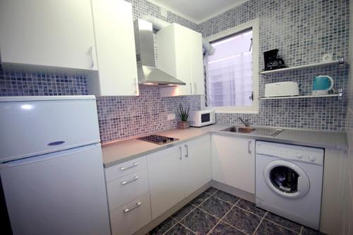a kitchen with white cabinets and a washing machine at Génesis Ramblas in Barcelona