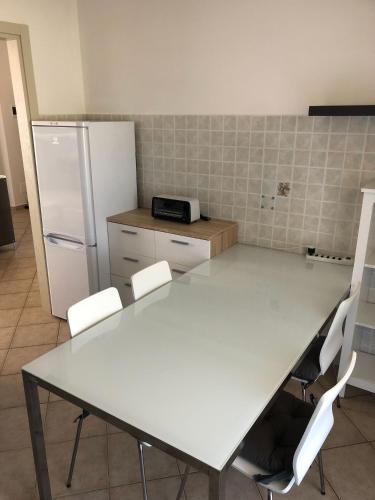 a kitchen with a white table and a refrigerator at Casa Vacanze Sunflower in Carrara
