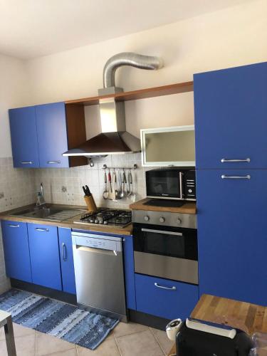 a kitchen with blue cabinets and a microwave at Casa Vacanze Sunflower in Carrara
