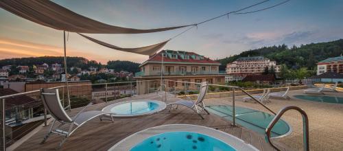 a balcony with chairs and a view of a city at Alexandria Spa & Wellness Hotel in Luhačovice