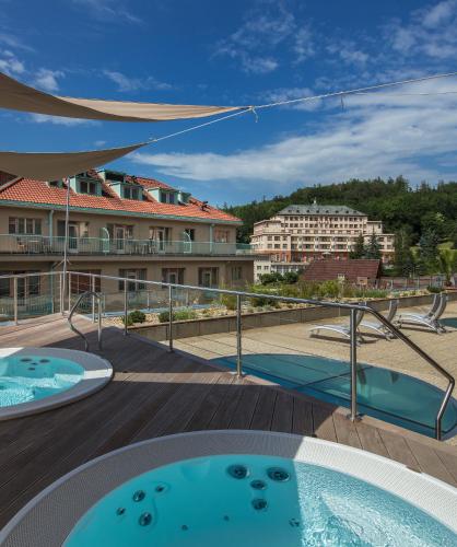 two hot tubs on the deck of a building at Alexandria Spa & Wellness Hotel in Luhačovice