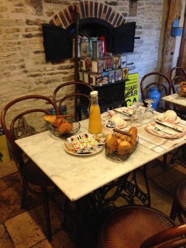a table with bread and baskets of food on it at Logis Hotel La Grange Du Relais in Colombey-les-deux-Églises