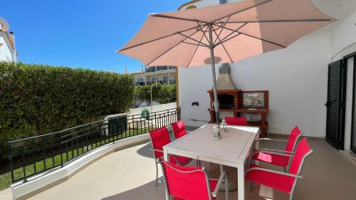 a table with red chairs and an umbrella on a balcony at Noly by Check-in Portugal in Albufeira