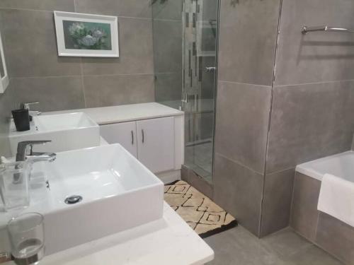a bathroom with a white sink and a shower at 61 KYALANGA UMHLANGA in Durban