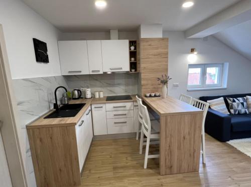 a kitchen with white cabinets and a blue couch at Apartmani Nova in Karlovac