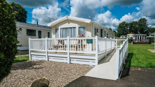 a white porch with a white fence on a house at Blairgowrie Holiday Park in Blairgowrie