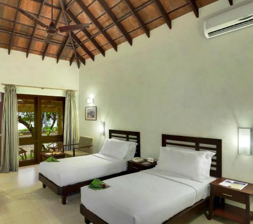 two beds in a room with white sheets at Abad Turtle Beach in Mararikulam