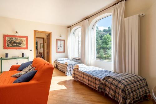 Cette chambre comprend deux lits, un canapé et une fenêtre. dans l'établissement Il Giardino del Sole - Lavanda, à Garlenda