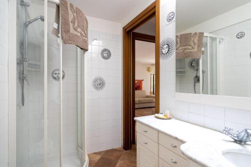 baño blanco con ducha y lavamanos en Il Giardino del Sole, Chalet Salvia, en Garlenda
