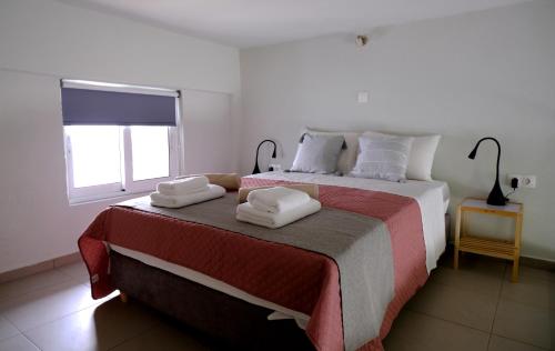Erinaki Apartments في كيساموس: غرفة نوم بسرير كبير عليها مناشف