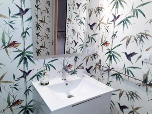 La salle de bains est pourvue d'un lavabo blanc et de papier peint ornithologique. dans l'établissement One bedroom house with enclosed garden and wifi at Parada, à Parada
