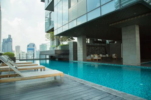 a swimming pool with lounge chairs and a building at Sukhumvit 11#Luxury#Pool#Gym#BTS Nana&MRT Sukhumvit#1BR#Max2ppl in Bangkok