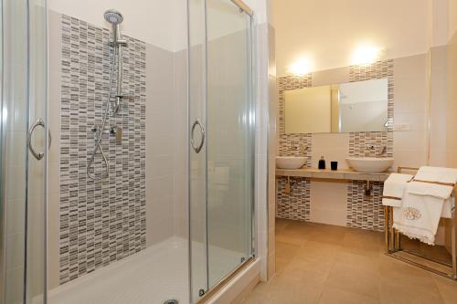 a bathroom with a glass shower and two sinks at San Vito Suites in Rome