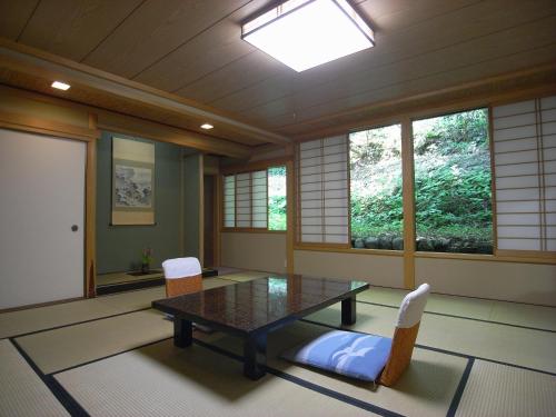 a dining room with a table and chairs and windows at Motoyu Ishiya in Kanazawa