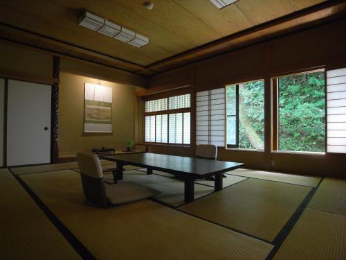 a dining room with a table and chairs and windows at Motoyu Ishiya in Kanazawa