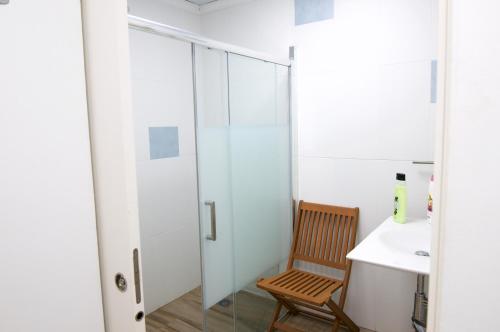 a bathroom with a shower and a wooden chair next to a sink at Lux Valentia Olta Calpe in Calpe