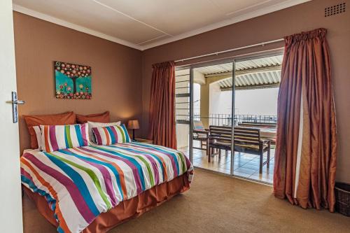 a bedroom with a bed and a balcony with a table at Seaside At 22 Sandpiper in Ballito