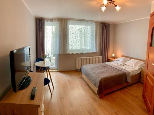 a bedroom with a bed and a desk with a television at Portowa 35 in Kołobrzeg