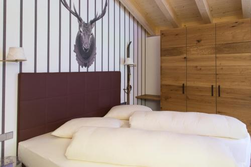 a bedroom with a bed with a deer head on the wall at Mountainlodge Luxalpine in San Vigilio Di Marebbe
