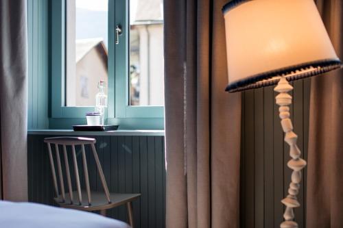 a lamp sitting next to a window in a room at Hotel De Londres in Brig