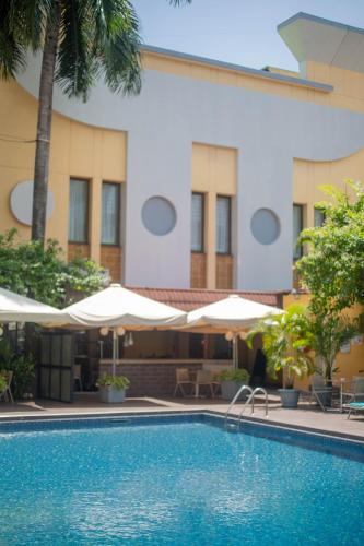a pool in front of a hotel with umbrellas at Hotel Memling in Kinshasa