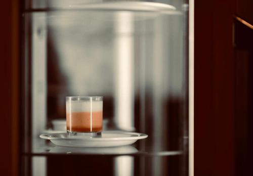 a glass on a plate on a table with a drink at Hotel Memling in Kinshasa
