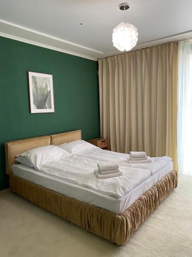 a bedroom with a large bed with a green wall at Garden Hall in Ternopilʼ