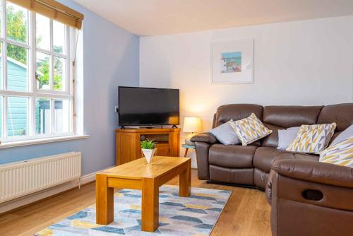 a living room with a couch and a tv at Falmouth Bay Holiday Apartments in Falmouth