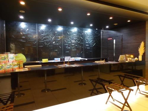 a room with a counter with chairs and tables at Dormy Inn Hakata Gion in Fukuoka