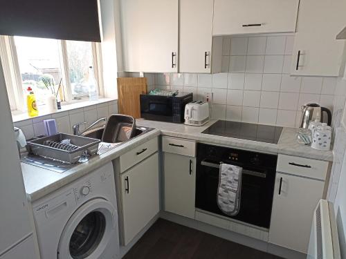 a kitchen with a sink and a washing machine at Froden Court in Billericay