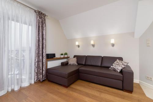 a living room with a brown couch in front of a window at Apartament Lux Rezydencja Tatry by Renters Prestige in Zakopane