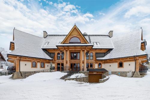 een groot houten huis in de sneeuw bij Apartament Lux Rezydencja Tatry by Renters Prestige in Zakopane