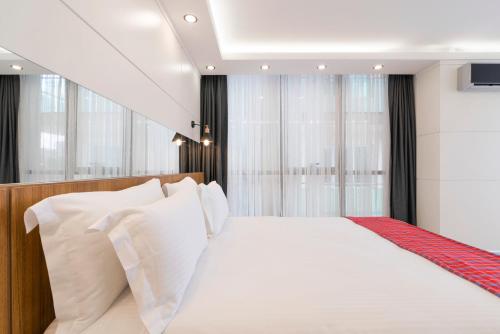 a bedroom with a white bed with white pillows at MAA Hotel and Suites - Hurlingham, Nairobi in Nairobi