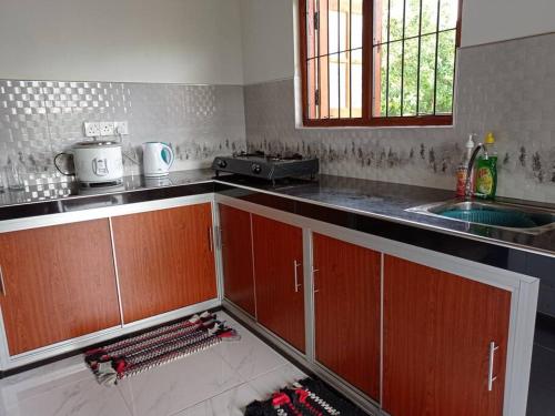 a kitchen with wooden cabinets and a sink at Saubagya Residence - Air Port View in Anuradhapura