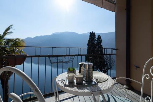 une table sur un balcon avec vue sur l'eau dans l'établissement Mamma Ciccia Holiday Home - Waterfront Apartment, à Mandello del Lario