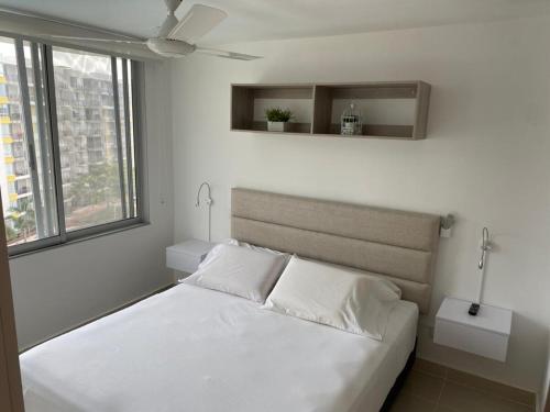 Cama blanca en habitación con ventana en Hermoso conjunto residencial con piscina! en Ricaurte