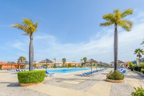a pool at a resort with palm trees and chairs at Casa Sunny Days - Boavista Resort in Lagos