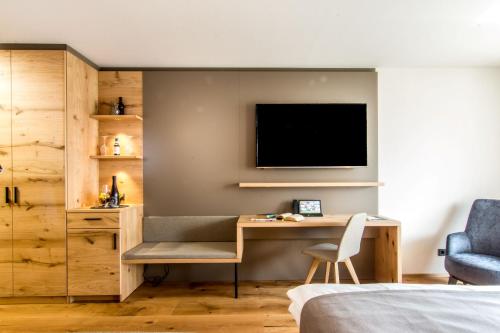 a bedroom with a desk and a tv on a wall at Wirthshof Hotel & Chalets in Markdorf