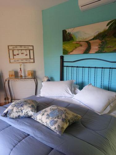 a bed with two pillows and a painting on the wall at Pousada da Lua São Pedro in São Pedro