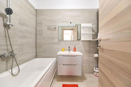 uma casa de banho com uma banheira branca, um lavatório e uma banheira tubermott em Olive apartment in Spa n Pool Resort-parking em Mamaia