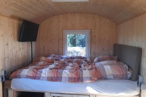 a bedroom with a bed in a wooden room at Zirkuswagen Glamping für 2 mit Veranda Küche Netflix Parken und Hofladen in Steinhöfel
