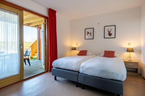 a bedroom with two beds and a sliding glass door at Grimaud 141 - Kustpark Village Scaldia in Hoofdplaat