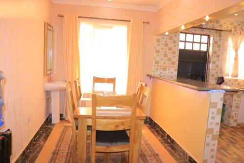 a dining room with a table and a kitchen at The Glamour House in Juja