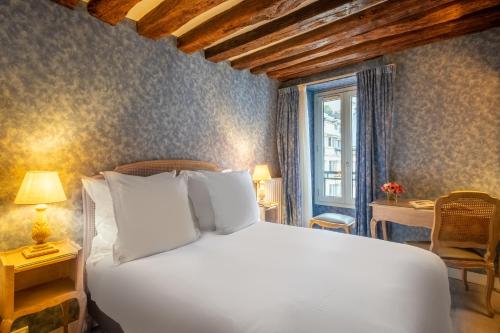 a bed with white pillows in a room with a window at Hôtel Baudelaire Opéra in Paris