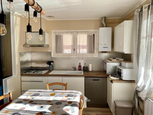 une petite cuisine avec une table et un évier dans l'établissement Maison rénovée en plein cœur des Cévennes, à Villeneuve