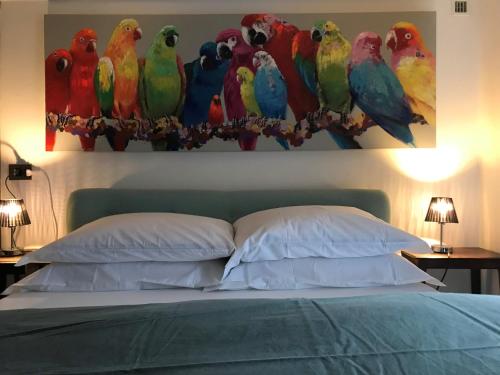 una pintura de loros en una pared sobre una cama en LA PLAYA Cottage con spiaggia privata, en Pettenasco