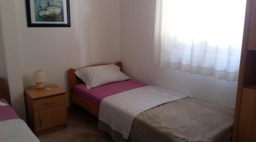 um pequeno quarto com 2 camas e uma janela em Apartments Mis - apartments close to sea em Petrcane