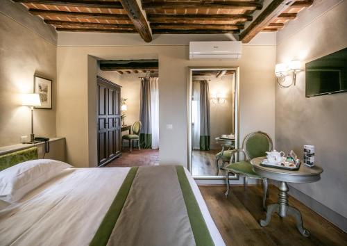a bedroom with a bed and a table and chairs at Palazzo Leopoldo Dimora Storica & Spa in Radda in Chianti
