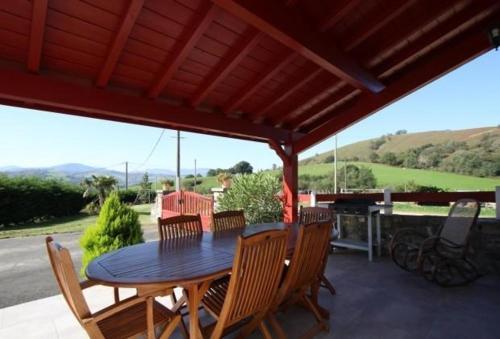 a table and chairs on a patio with a roof at Gîte à la Ferme Larranda in Suhescun